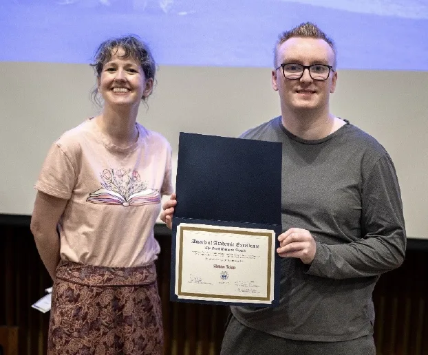 Daisy Milman standing to the left of Aidan Kipp holding an award.
