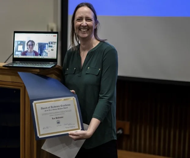 Jessica Lindoerfer presenting an award next to a computer screen with Lee Dufresne.