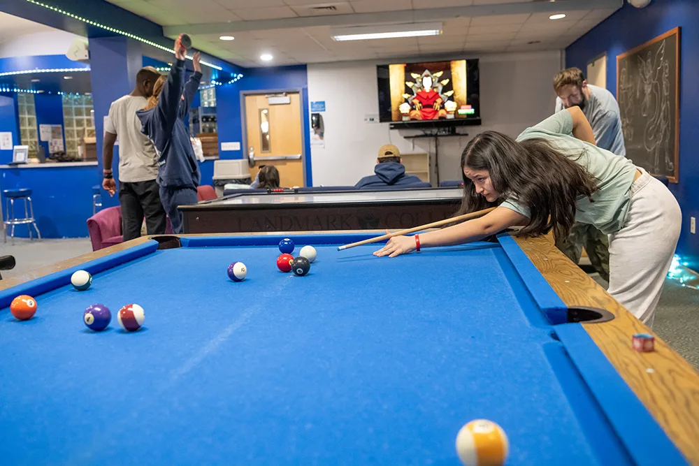 A group of students play billiards and watch television in the Strauch Center.