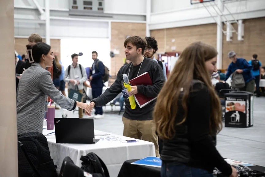 A smiling student shaking a featured employers hand at the fall 2025 career fair.