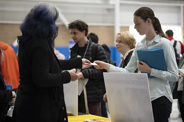 People exchanging information at a booth during a networking event.