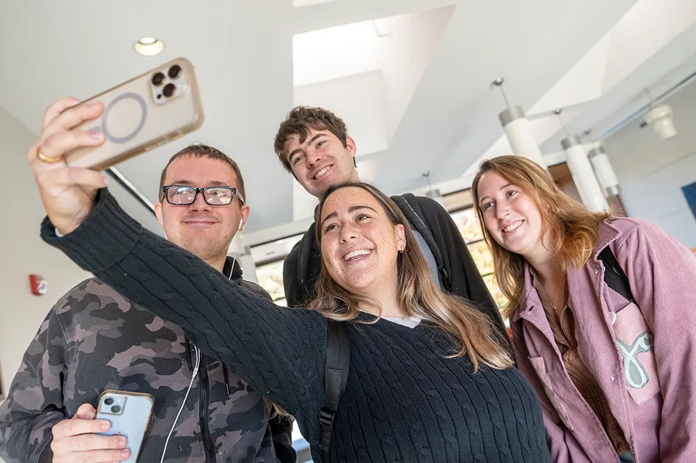 Four smiling students taking a group selfie