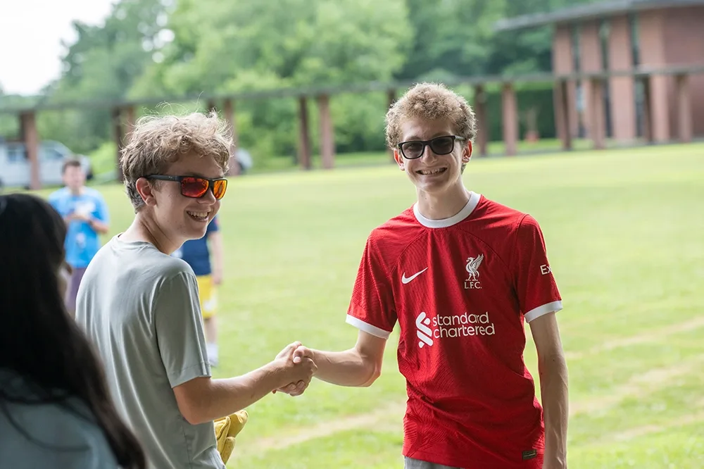 Two students shaking hands on the quad.