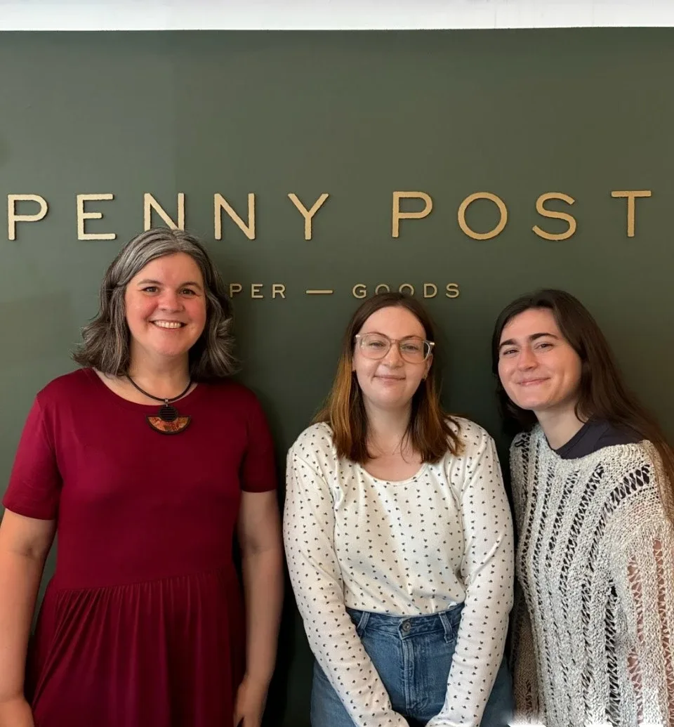 Jules Seely-Power photographed in front of the Penny Post store logo with two of her coworkers.
