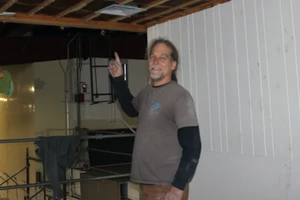 gray haired man pointing upwards at exposed ceiling rafters