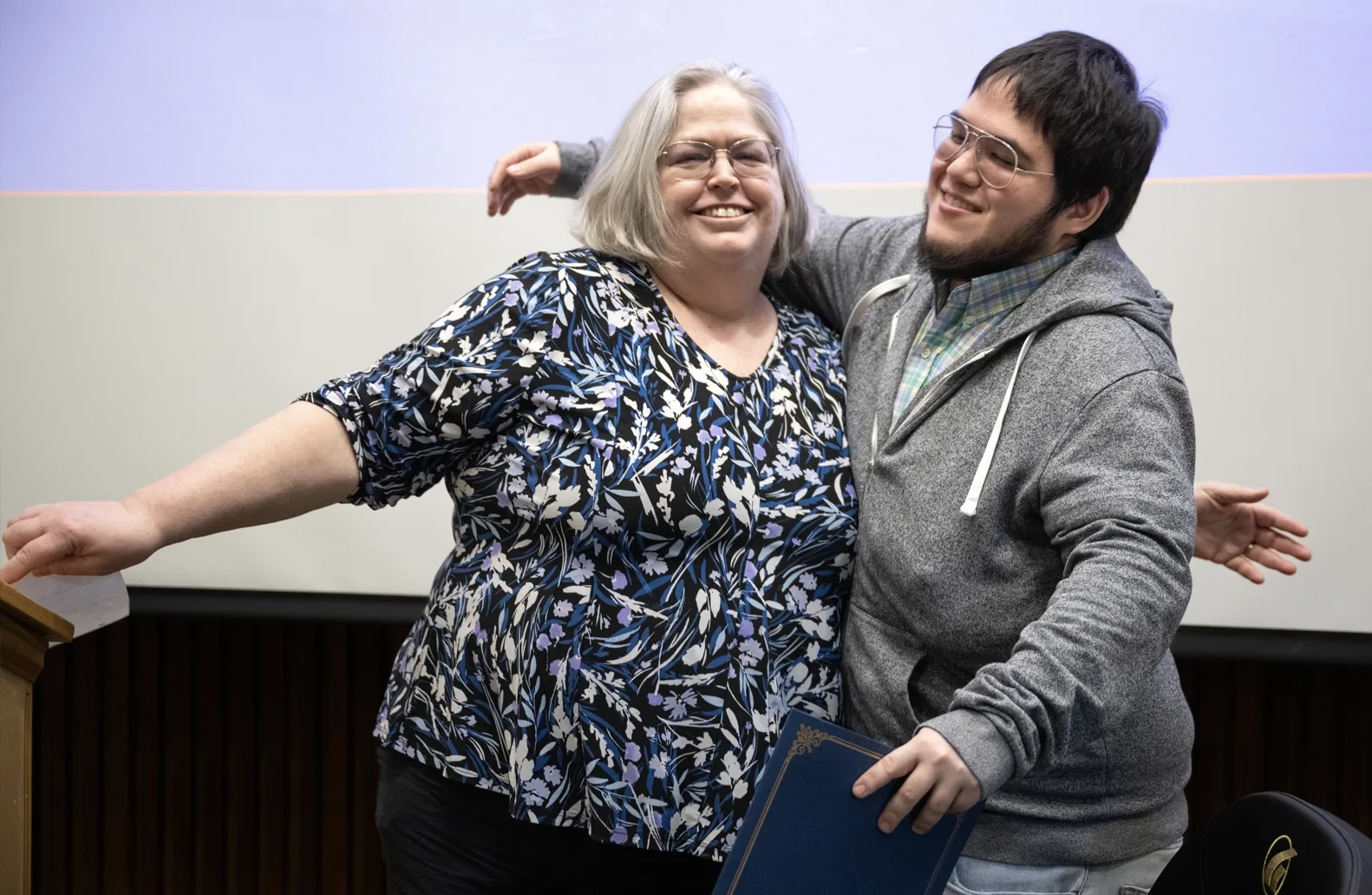 A professor and a student embrace as the student, right, accepts an academic award.