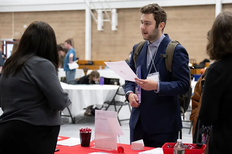 A student talking to a company representative at a career fair.