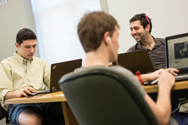 Three people at a table using laptops.