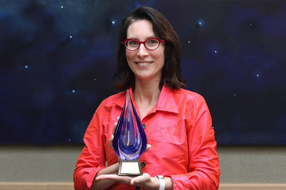 Theodora van Roijen '00 holding a glass award.