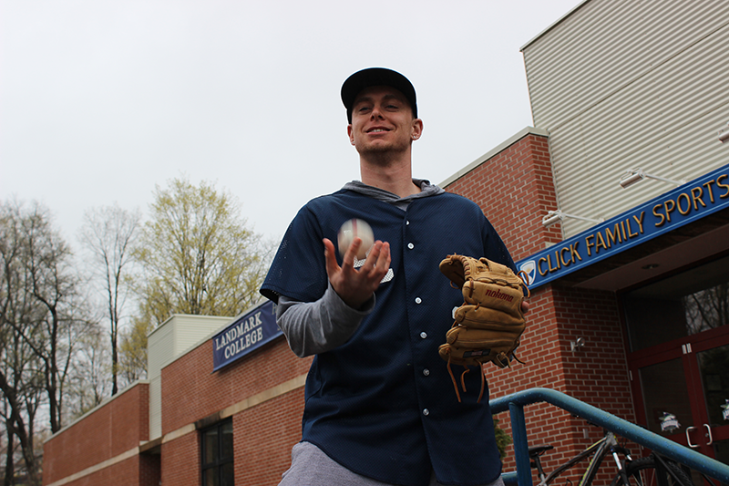 Patrick McKenna '14 wearing a baseball jersey and cap, holding a glove and tossing a baseball outside a sports facility.
