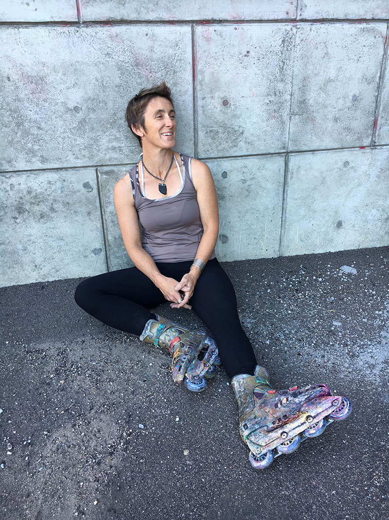 Woman in roller blades sitting with her back against a wall.