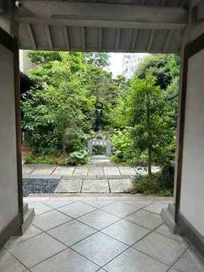 Entrance to a shrine, there is a statue of Buddha in the center surrounded by foliage