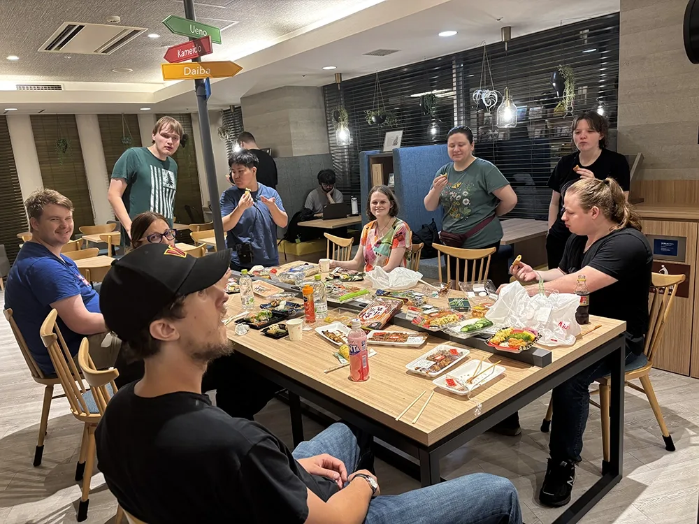 A group of students share a late-night meal around a table covered with convenience store food.