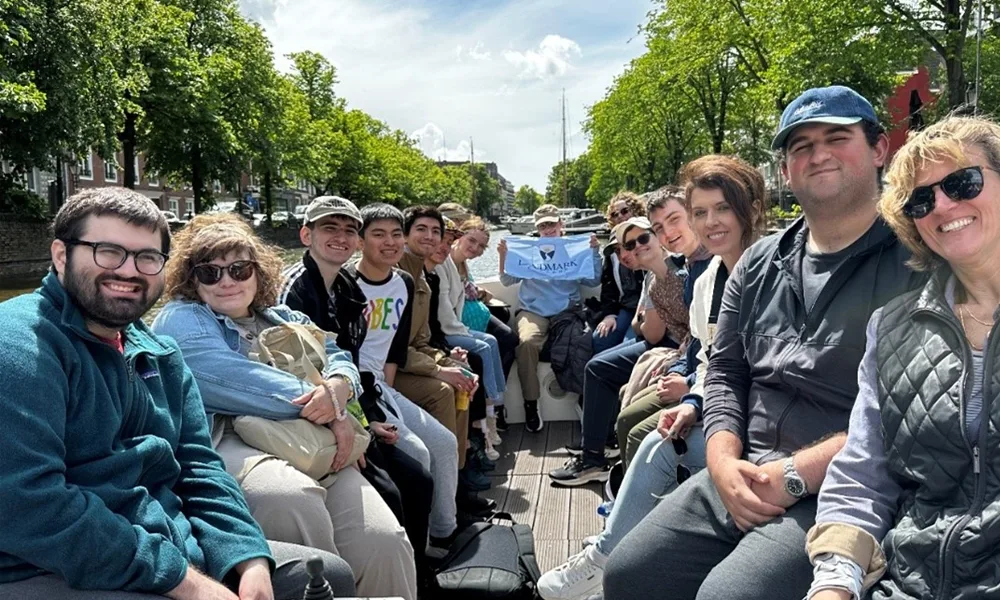 A group of smiling people riding a boat on a tree-lined canal