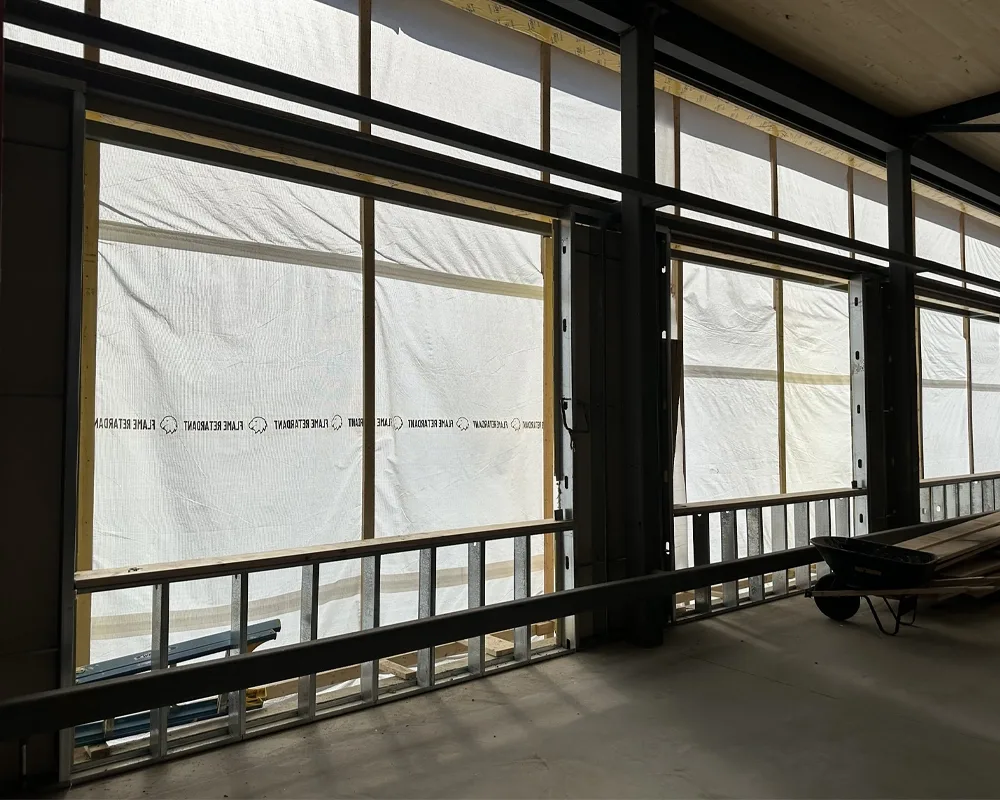 interior with sunlight coming through white building wrap of large windows
