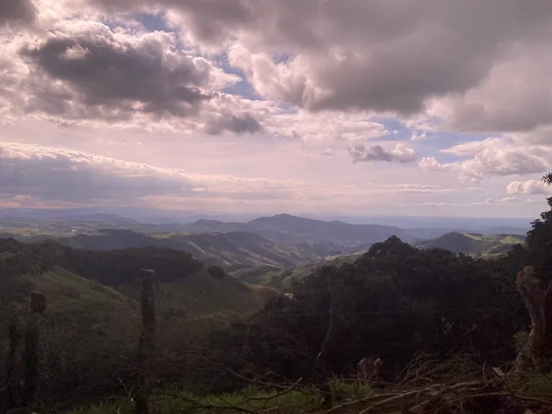 An elevated view of the green, mountainous landscape of Costa Rica with many clouds overhead.