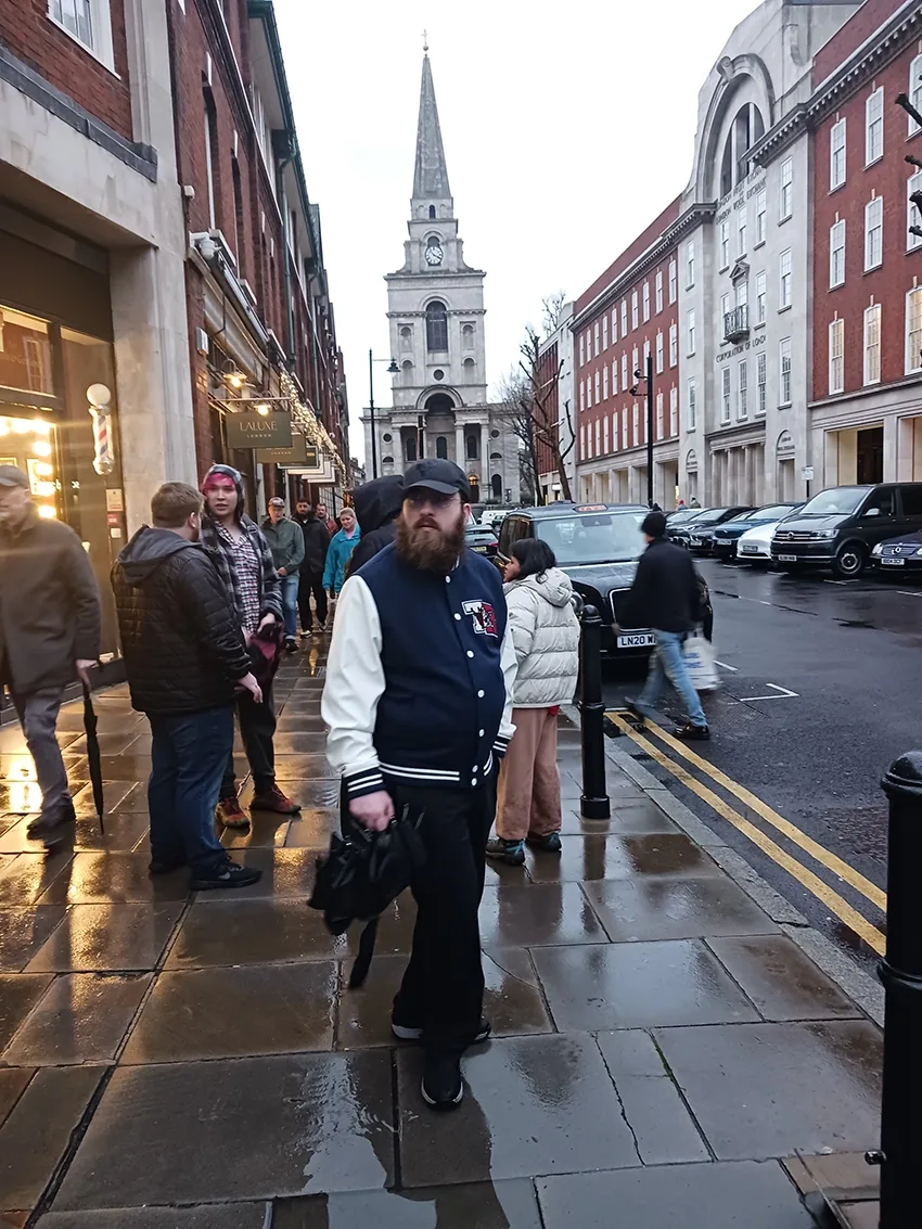 Student in blue jacket with white sleeves on rainy sidewalk