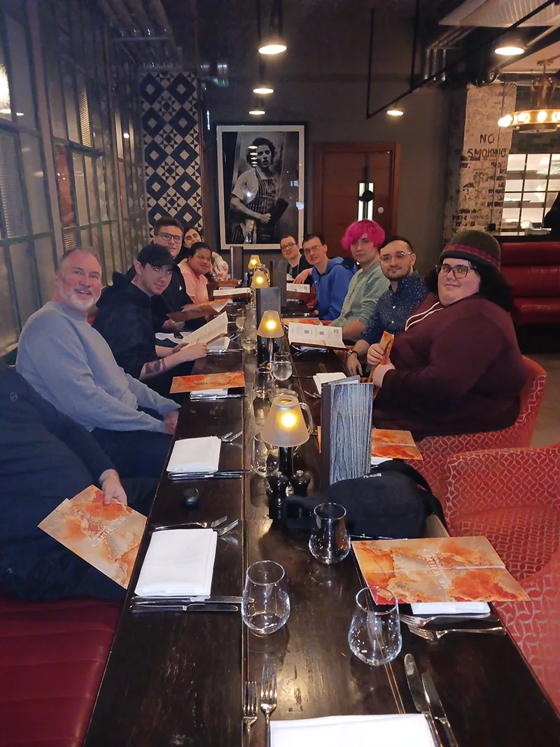 A group of 10 students and trip leaders post for photo sitting at a restaurant table