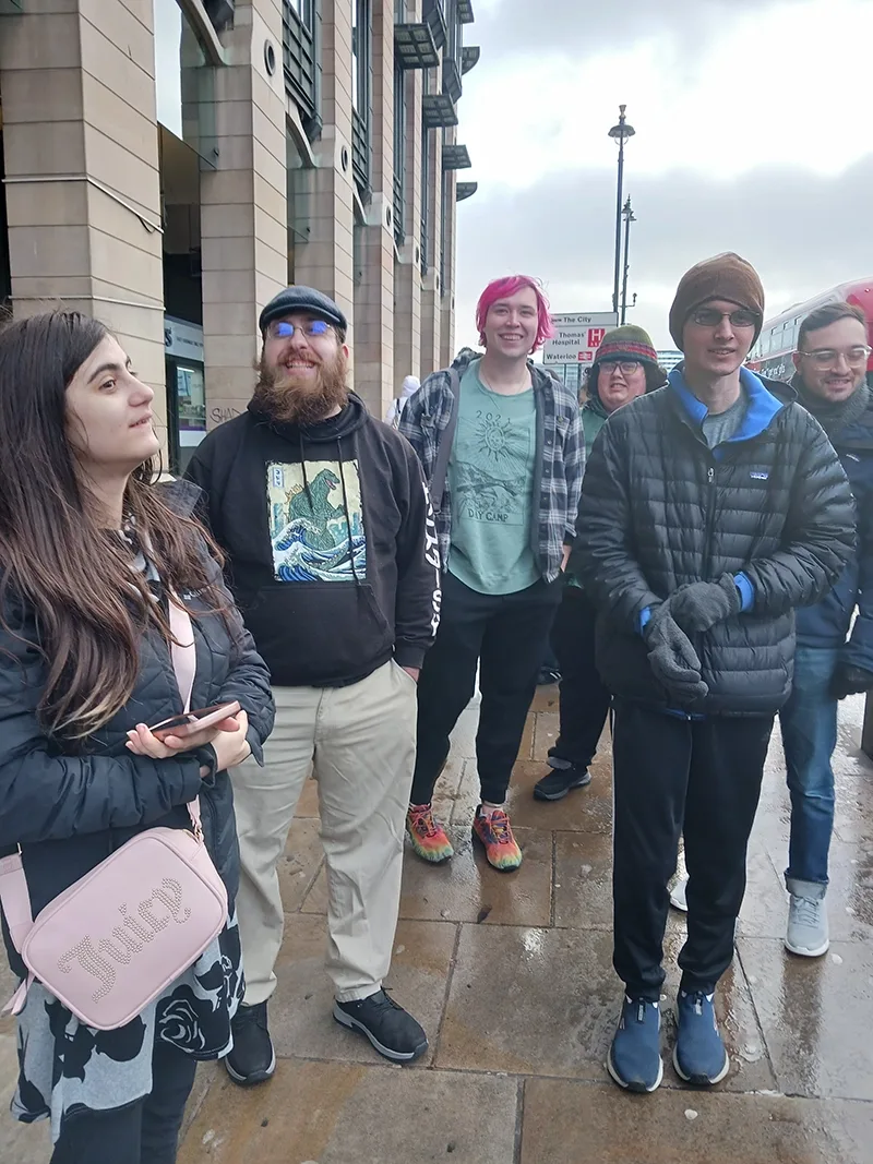 Five students stand on a sidewalk in central London