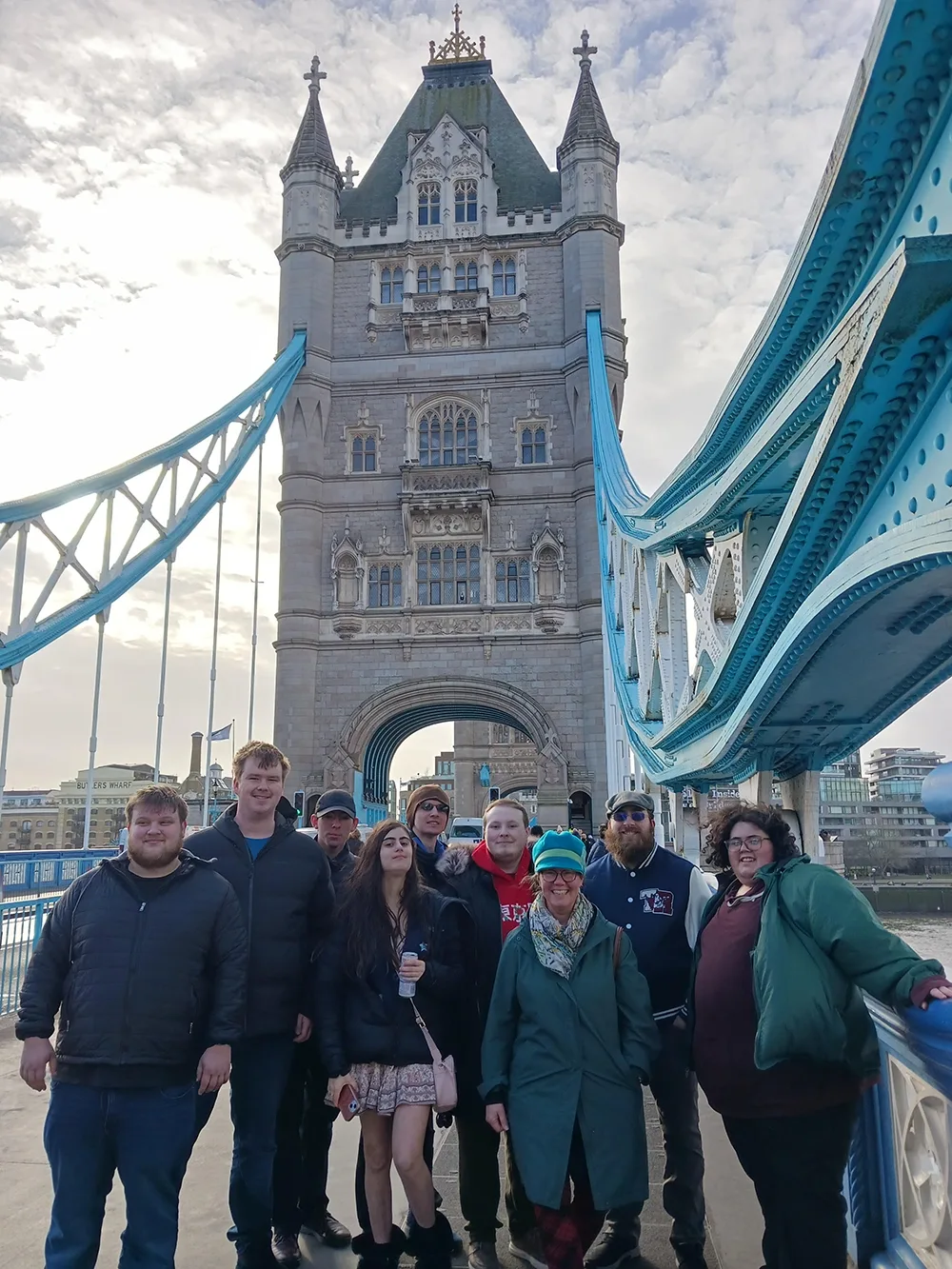 Six young men and one young woman stand with their instructor on Tower Bridge during a day out in London.