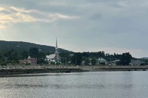 a rocky coastline alone a river with a quaint village in the background