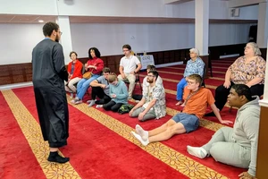 A man in a black robe talking to a group of people
