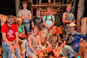 a group of students and their teacher inside an indigenous long house