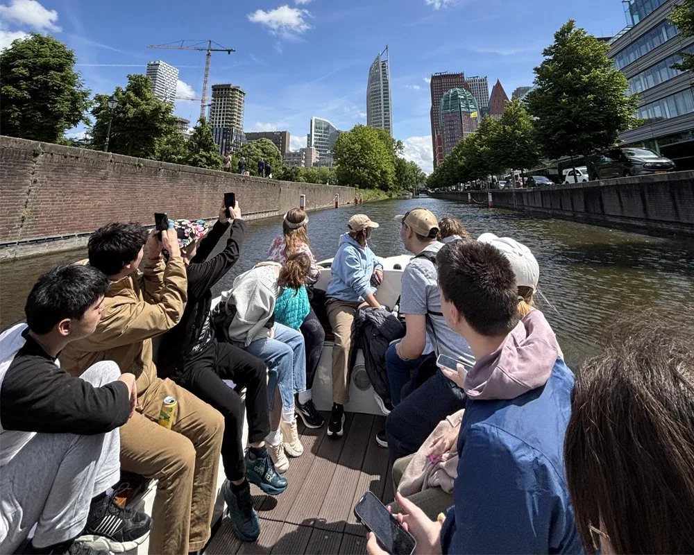 a photo of 16 people in a tour boat in a canal on a sunny day.