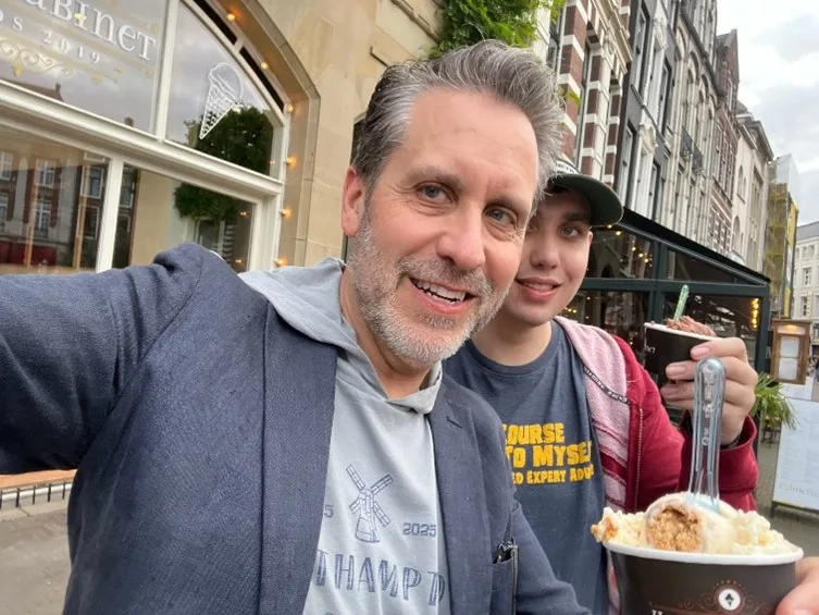 A man an his 21-year-old son stand on a street with cups of ice cream