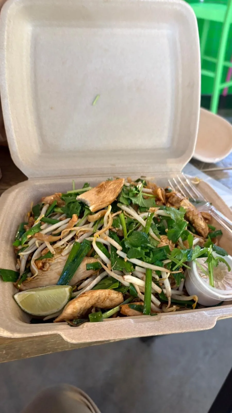 Open square takeaway box with PadThai noodle dish with fork already in it.