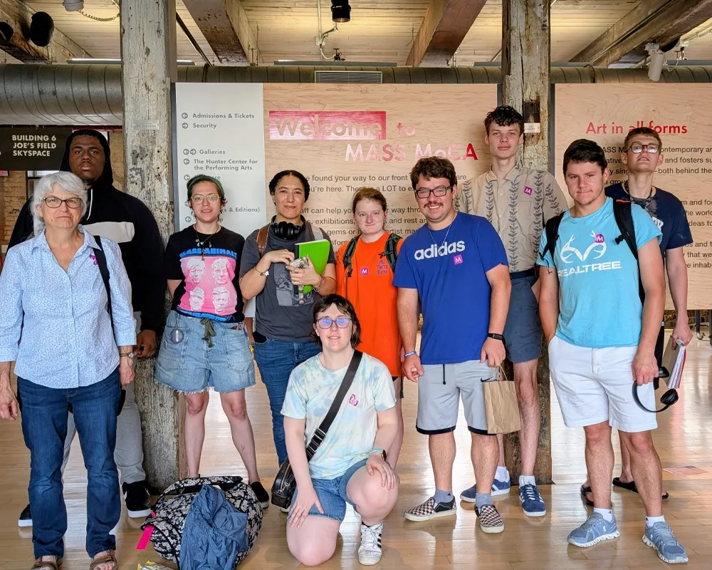 Group of students and faculty posing in front of sign at Mass MOCA