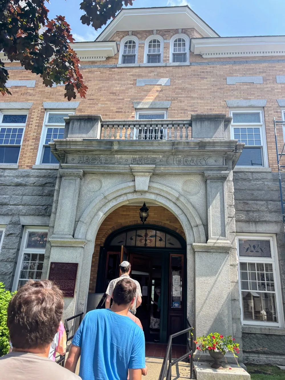 A group of student entering a building. The words "Haskell Free Library" are engraved in the stone above the entry.