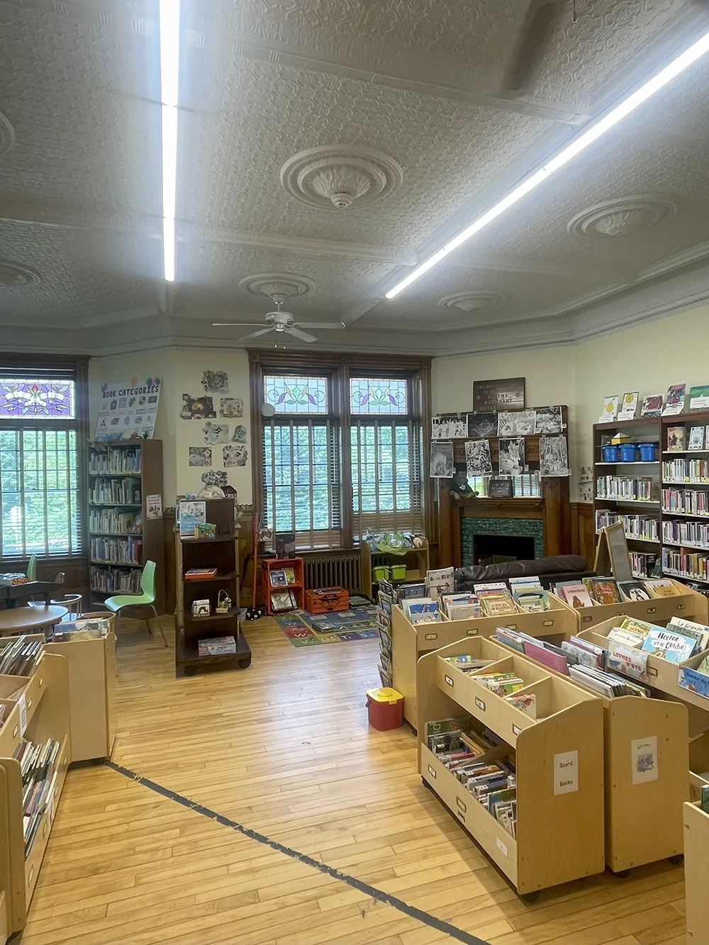 A photo of a black line on a wood floor with bookshelves around it.