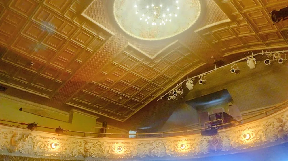 A lit chandelier with carved wood below it.