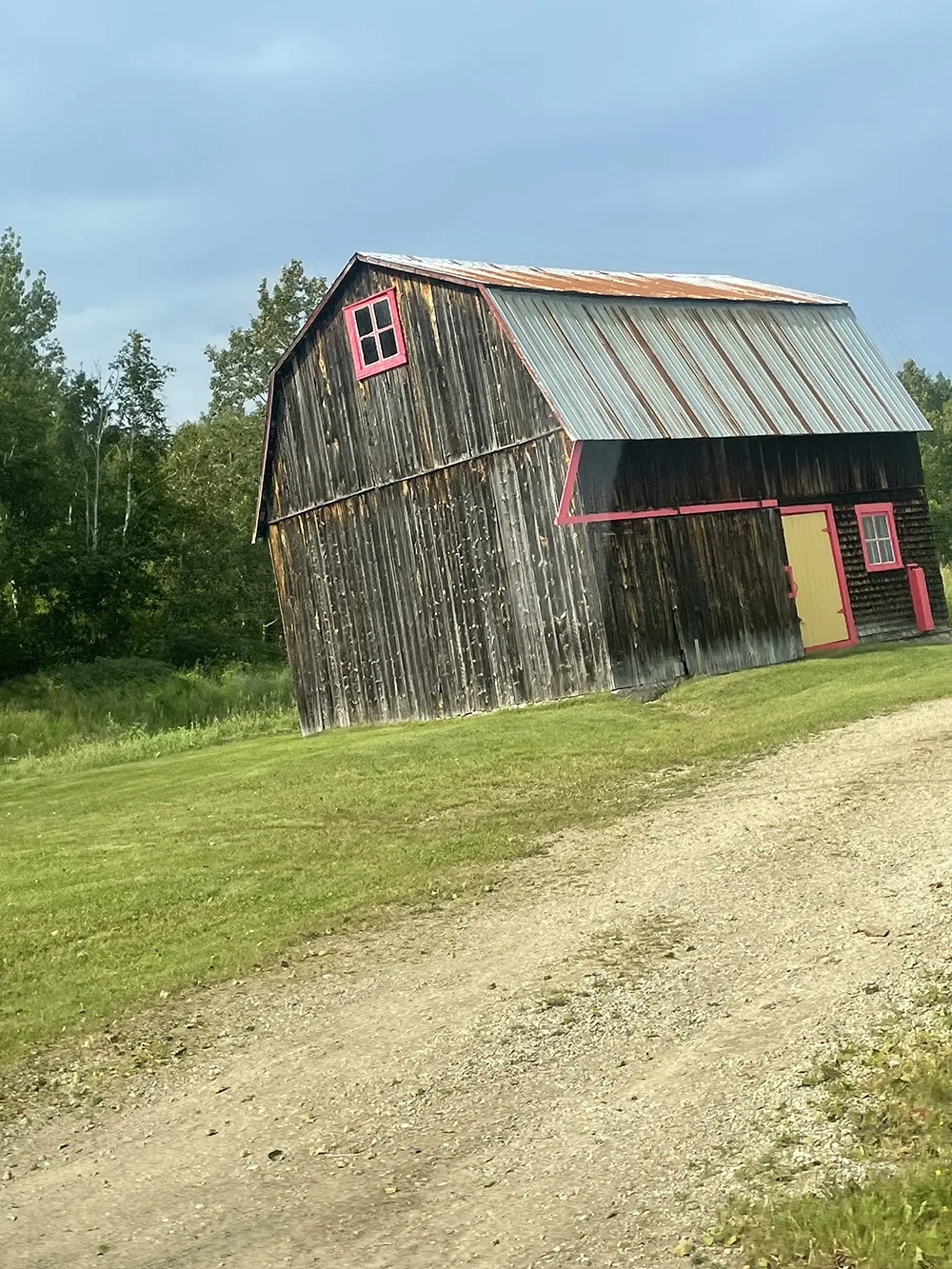 a rustic barn with a tree-covered hill in the background