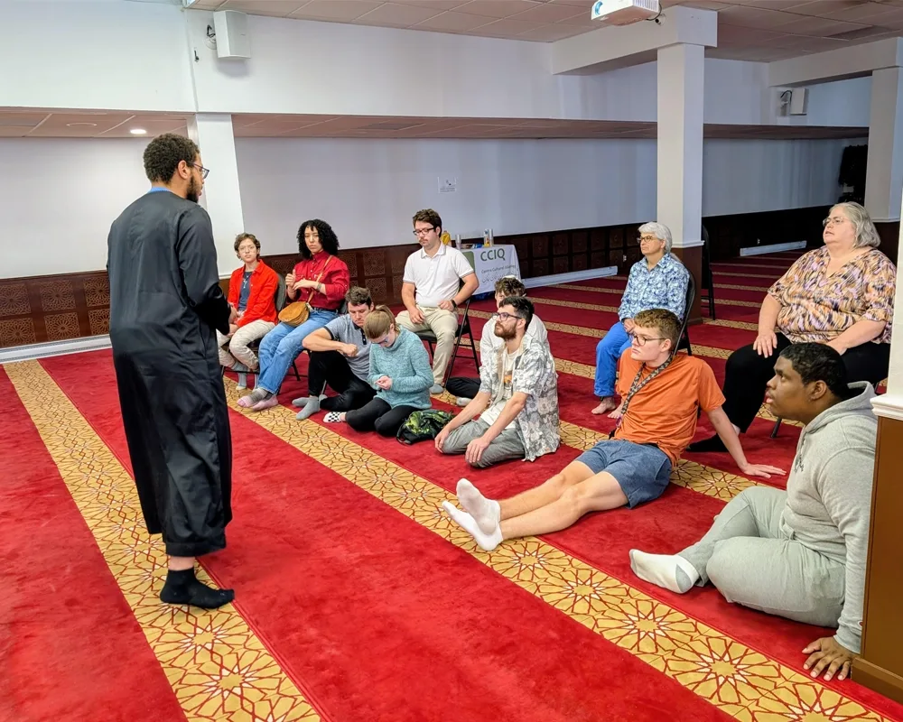 A man in a black robe talking to a group of people