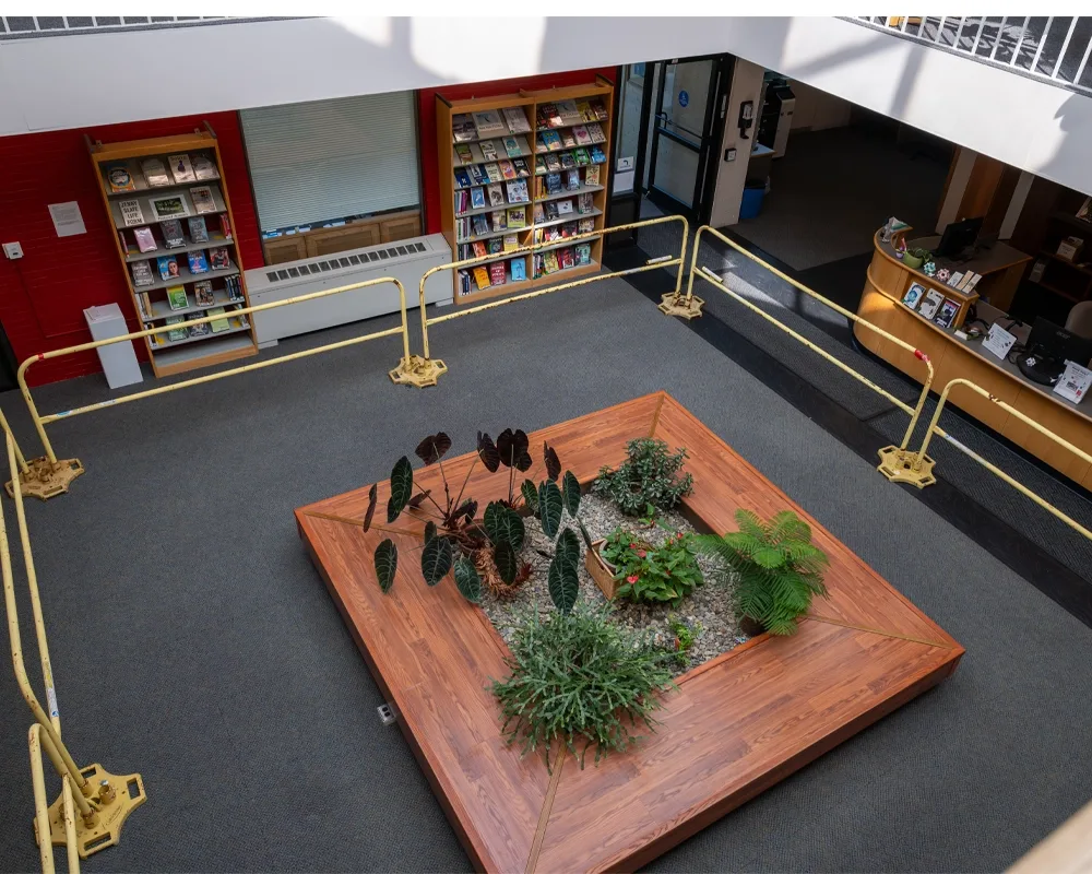 Overhead view of seating area below skylight on the main floor of the library. Metal railings have been placed around it for safety purposes