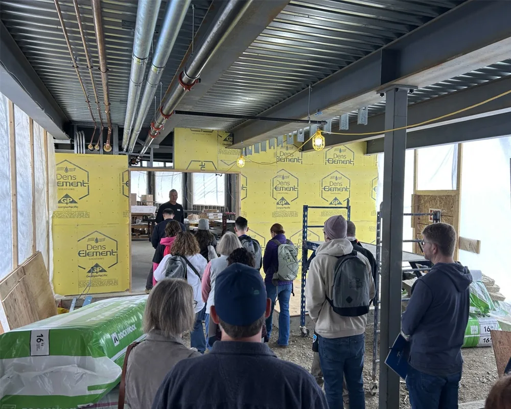 A group of about 20 people touring the inside of a building currently under construction