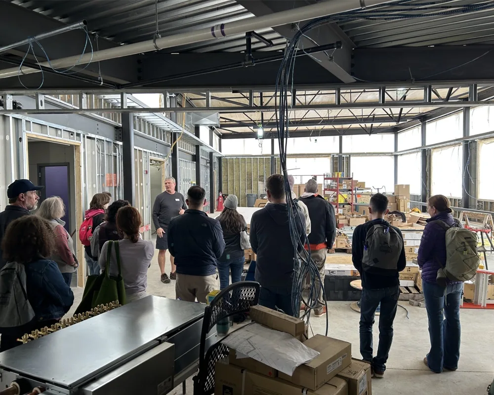 a group of people listening to a person talk inside a building under construction