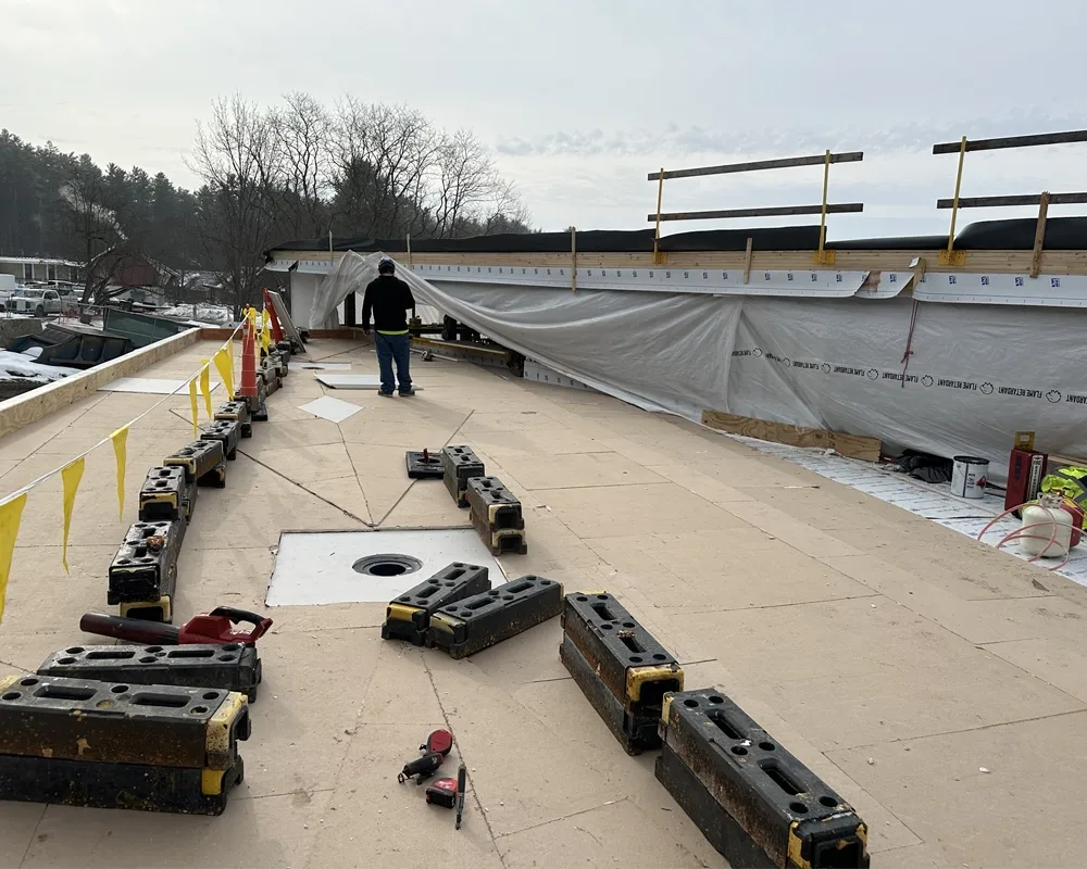 construction worker on roof of building with many segments of piping for roof drainage