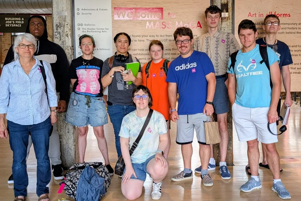 Student and faculty pose for a photo in front of an information board inside a museum
