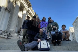 10 people on a set of stone steps outside a large building with columns