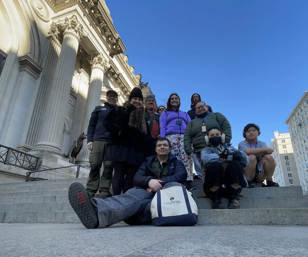 10 people on a set of stone steps outside a large building with columns.