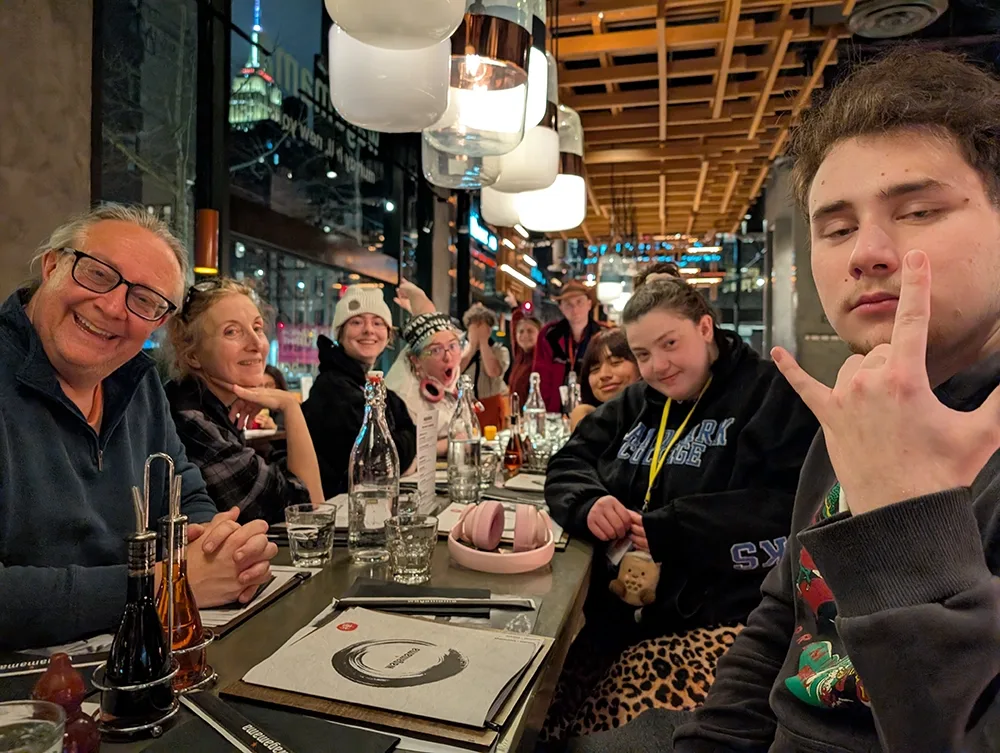A group of students posing around a restaurant table with the Empire State Building lit up in the background