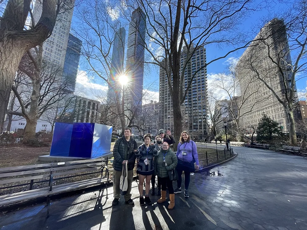 students posing in front of large blue sculpture in a park in downtown New York City