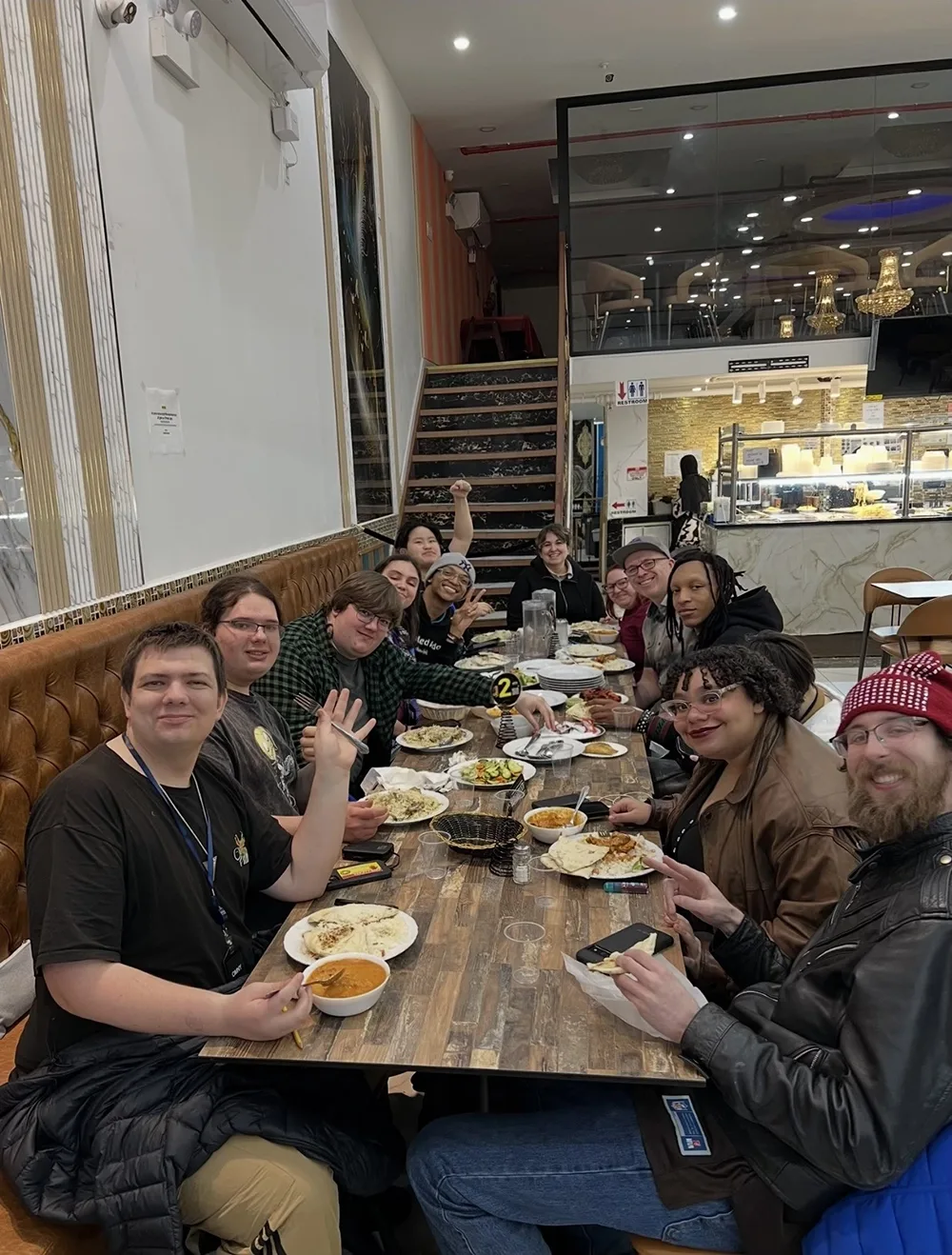 12 people sitting around a long wooden table in restaurant