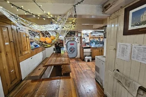Kitchen area on ship with long wooden table, refrigerator, and sink