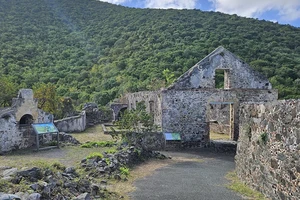 Several stone structures with a green hillside behind