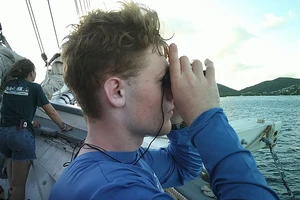 male student on ship looking through binoculars