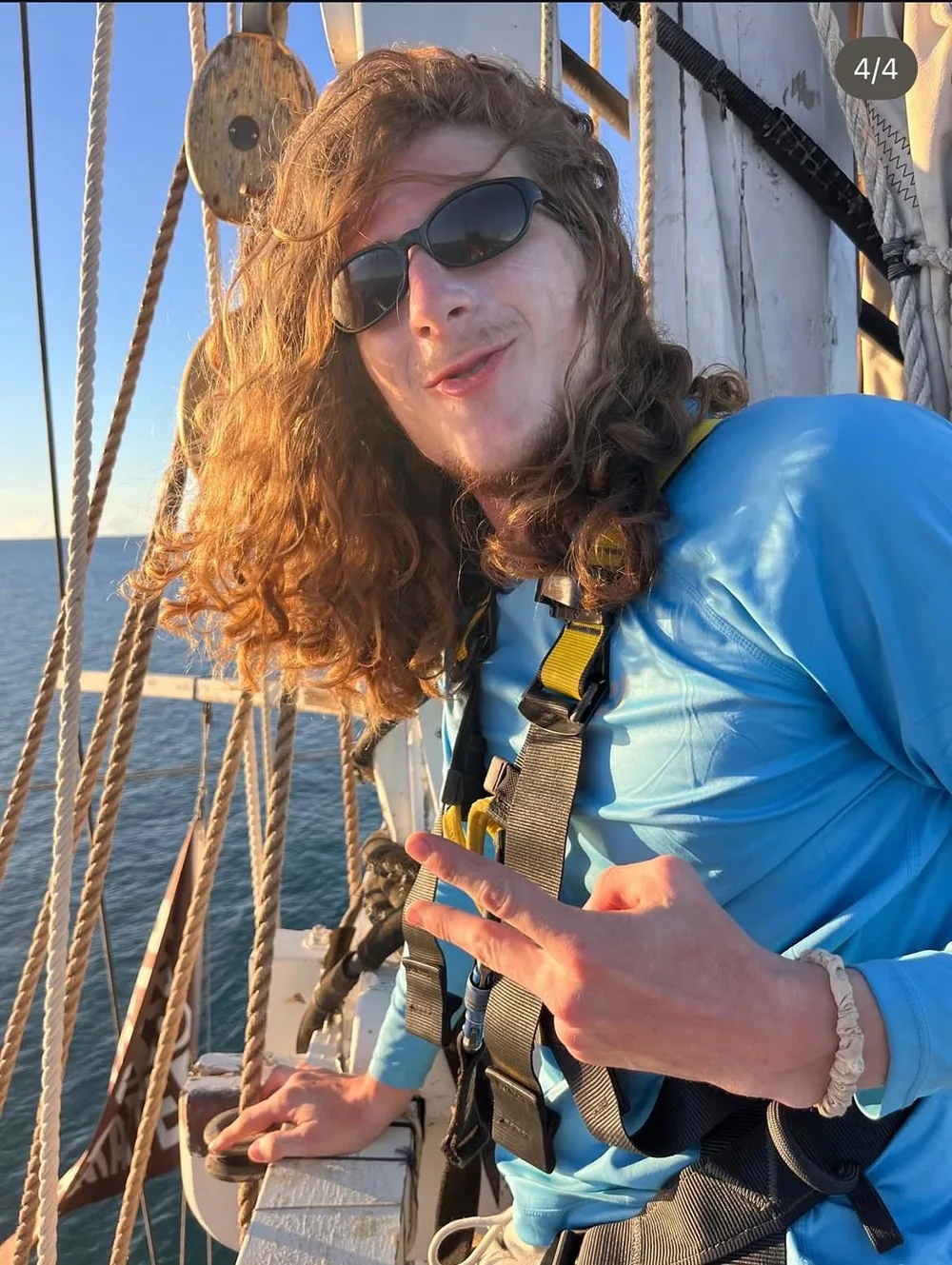 a student wears a harness standing near the rigging of a ship
